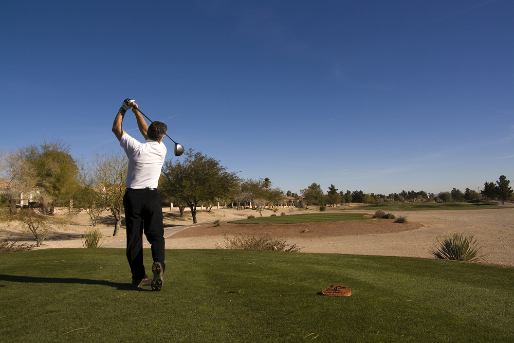 Man teeing off at Las Vegas golf course in the desert.