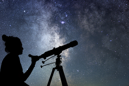 A woman stargazing with a telescope.