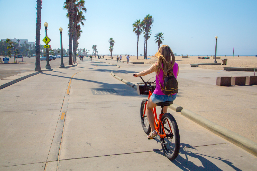 Woman riding a bike down Venice Beach in Los Angeles.