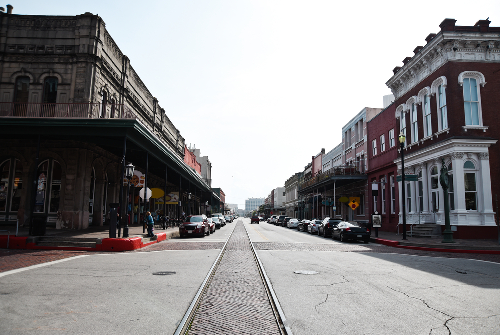 Restored buildings along a street with a train track running through the middle in Galveston, Texas.