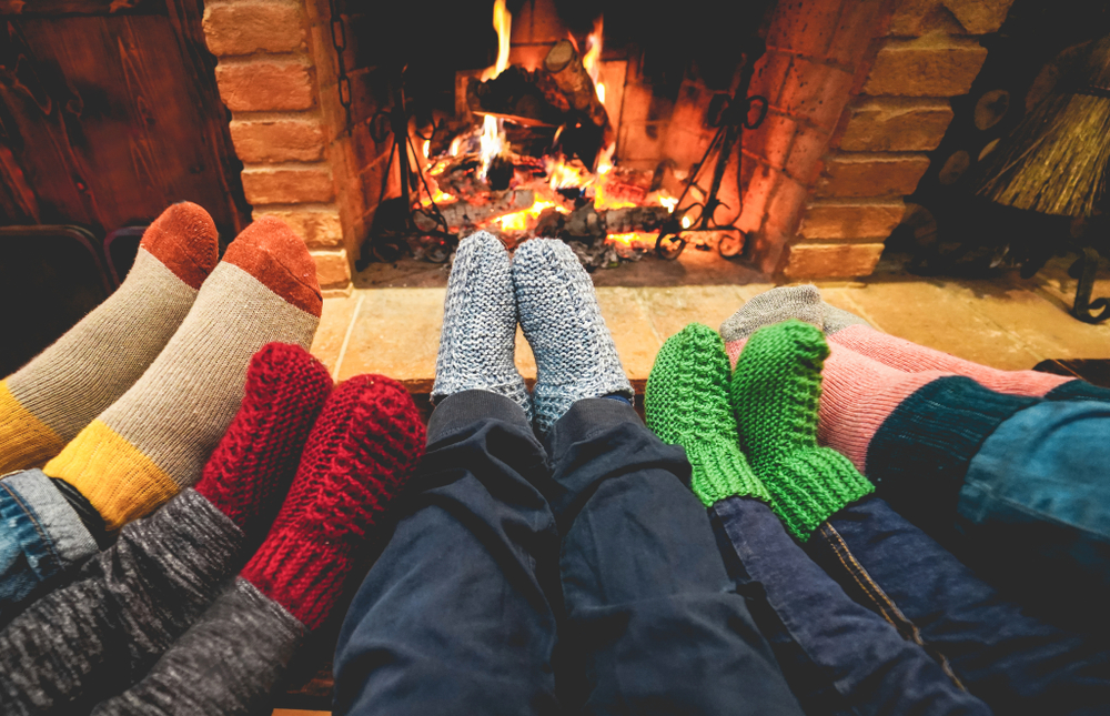Legs view of happy family wearing warm socks in front of fireplace.