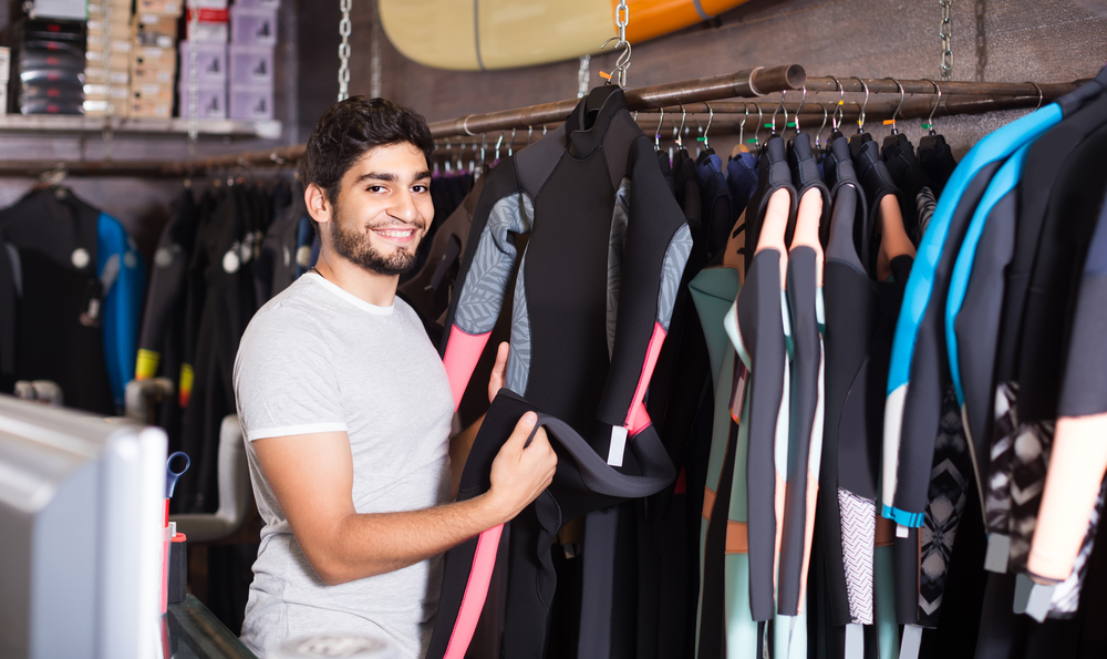 Man choosing a surf suit at a shop, one of the fun things to do in Cocoa Beach.