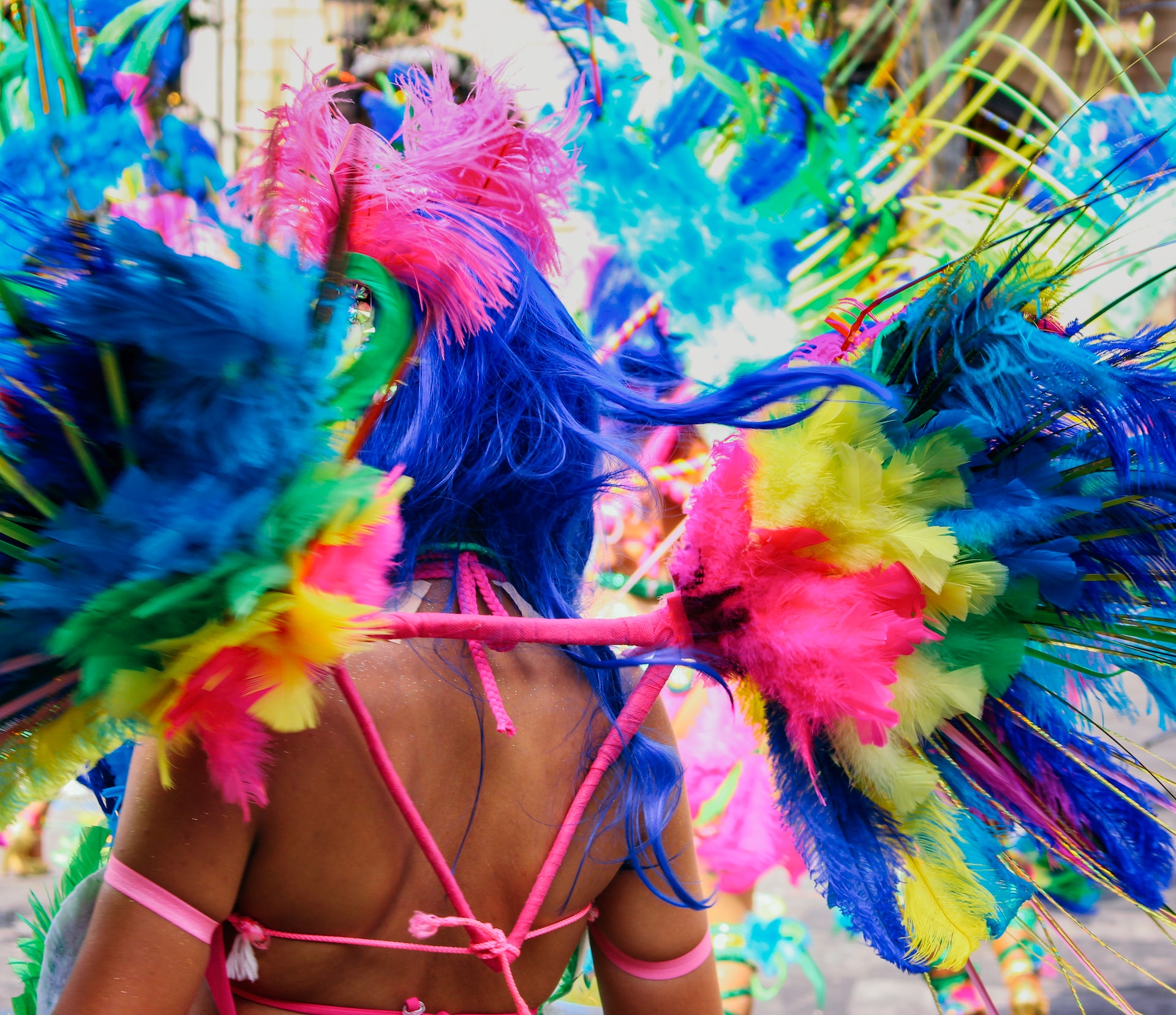 A woman wearing multicolored feathers and bikini with blue hair during Mardi Gras.