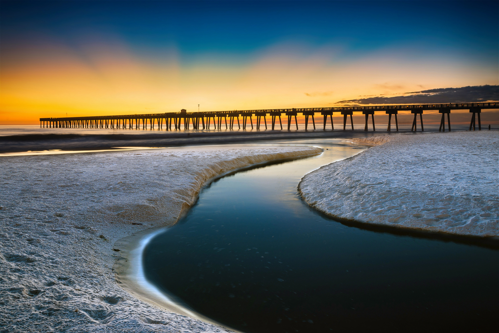 Beach scene in Panama City Beach, Florida, after sunset, a long wooden pier still illuminated by the fading light.