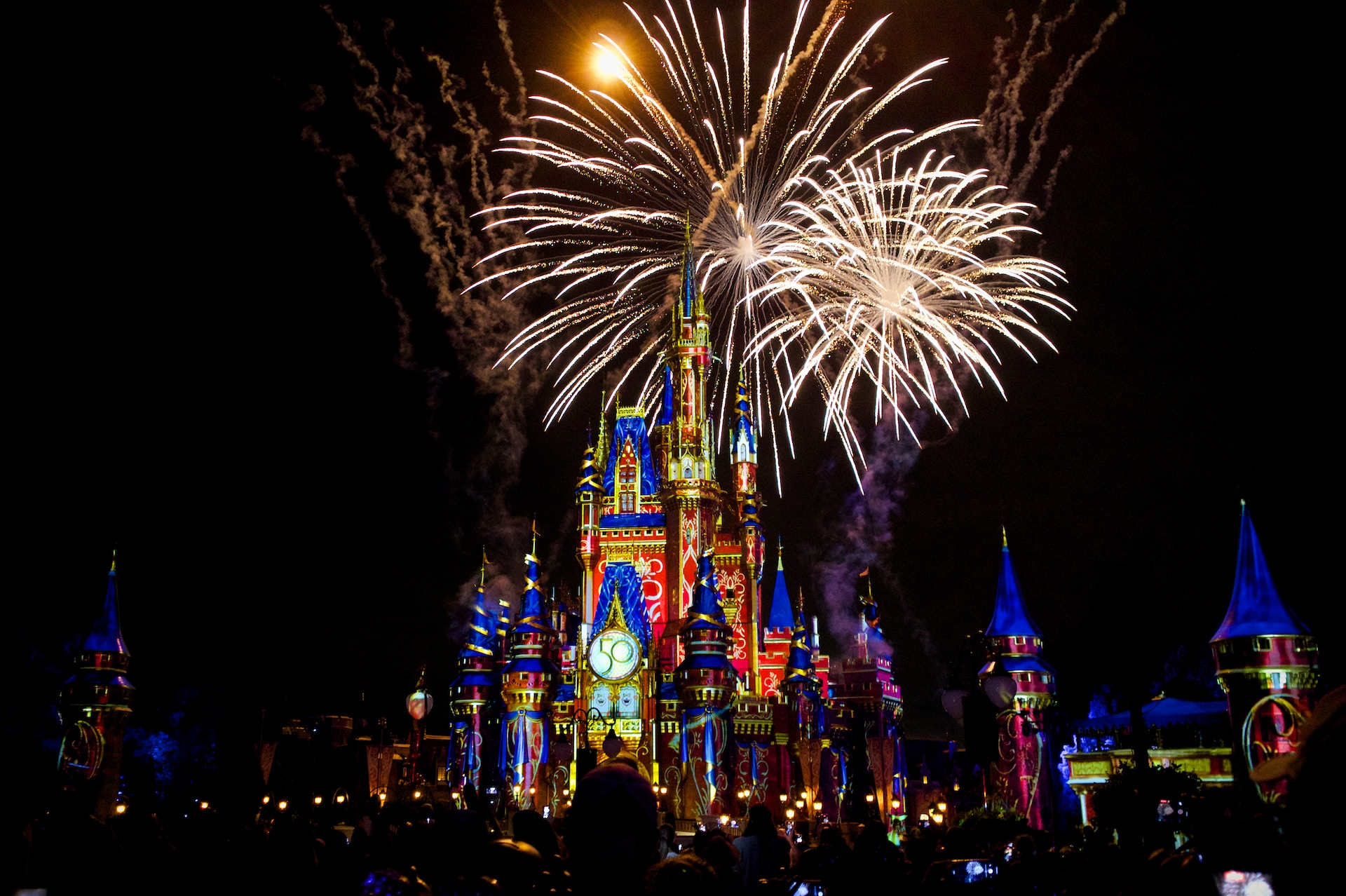 Disney castle at night with fireworks exploding around it.