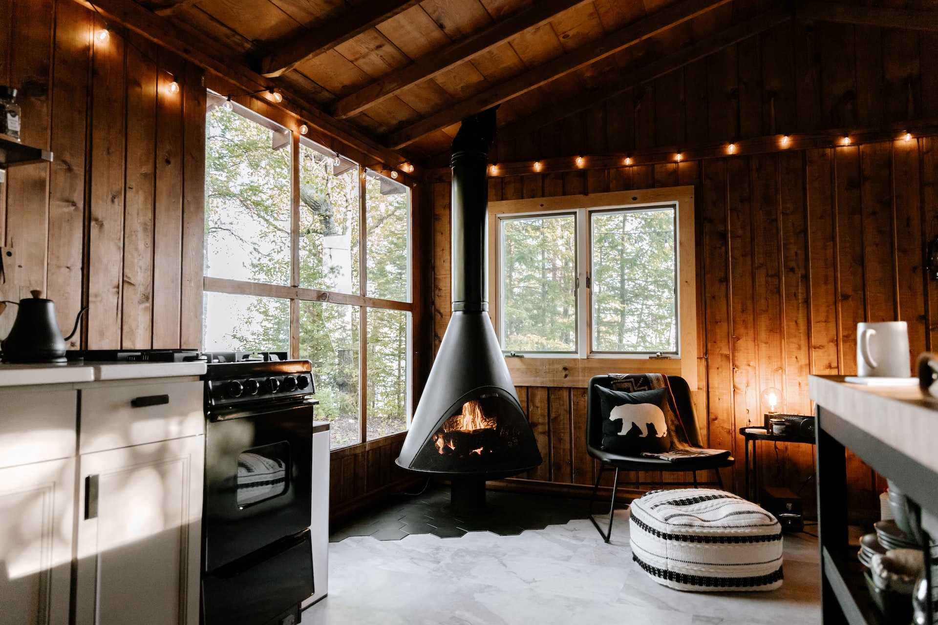 A modern interior of a high end cabin with a wood burning stove in the center.