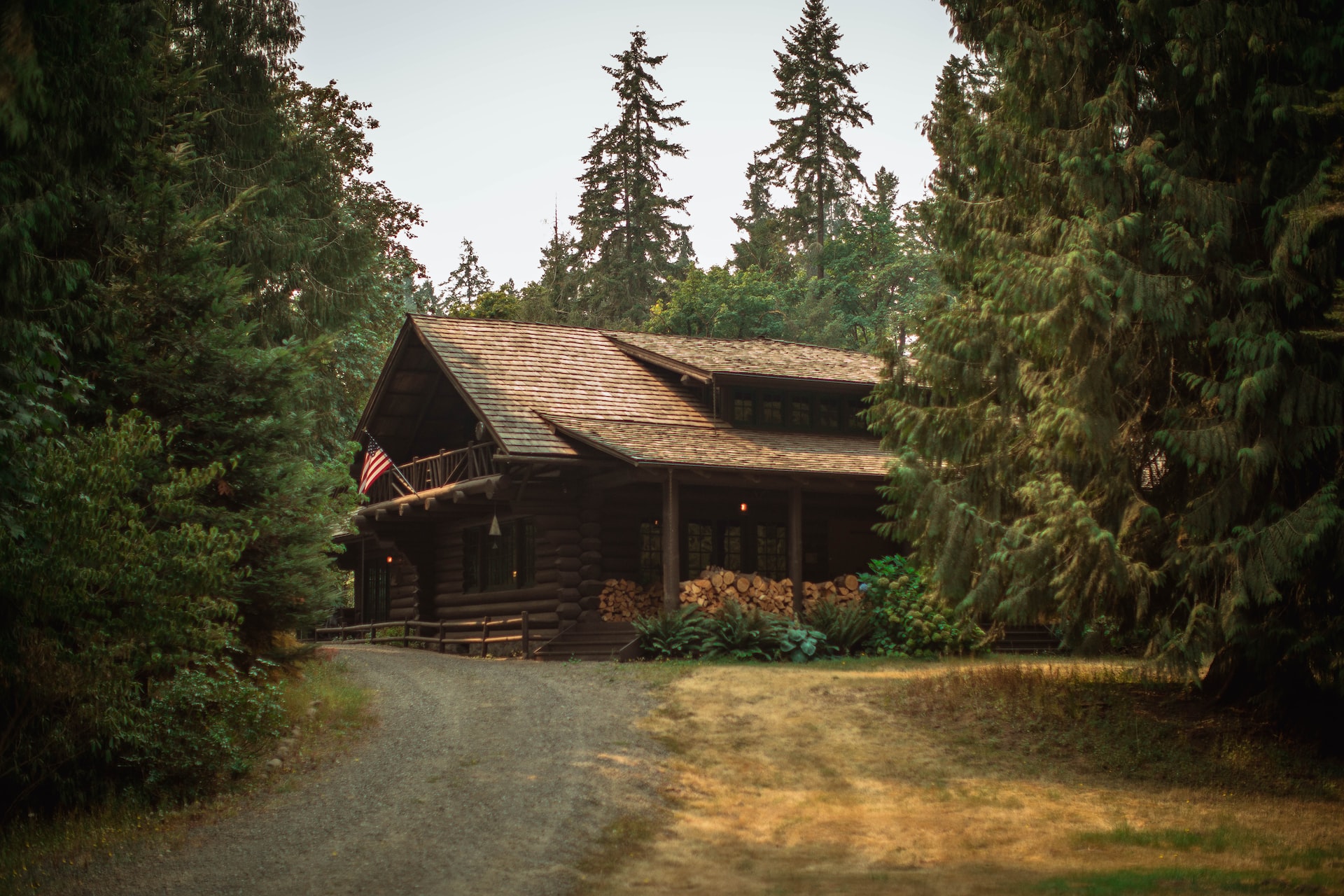 A large cabin in the woods with a bunch of chopped fire wood.