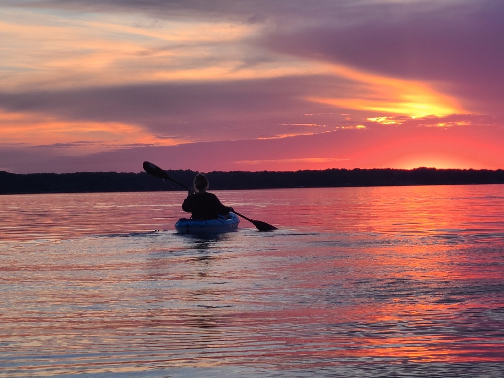 Kayaker on Torch Lake during sunset.
