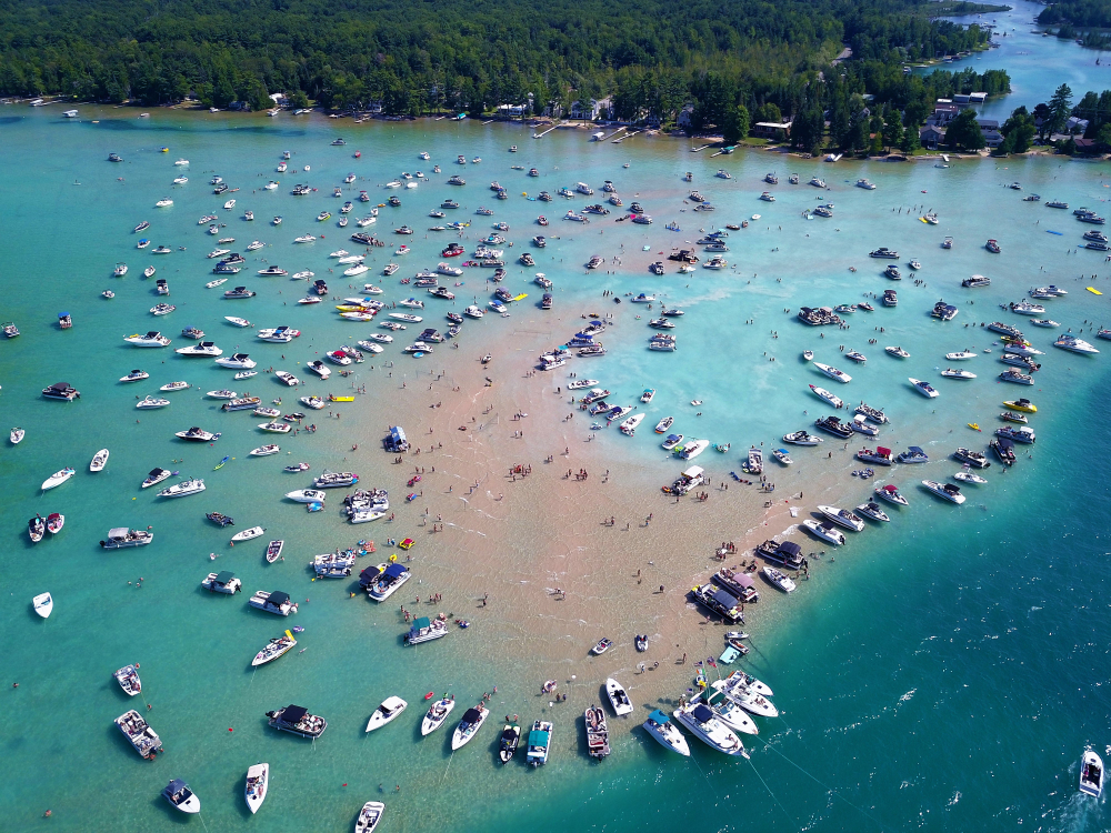 Hundreds of boats congregating around a sandbar as seen from an aerial perspective.