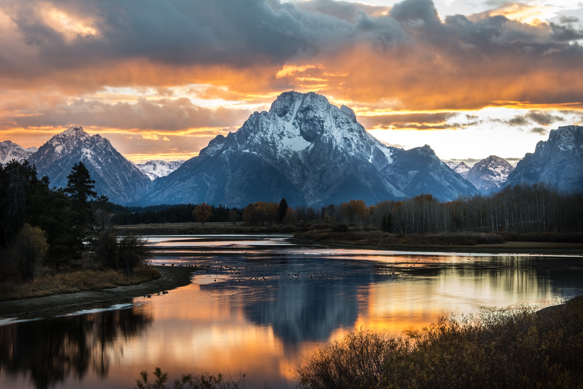 The Grand Tetons with snow on their peaks with the Oxbow Bend of the river in the foreground.