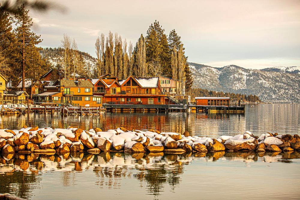 A snowy lake scene with buildings and rocks along the shoreline in North Lake Tahoe.