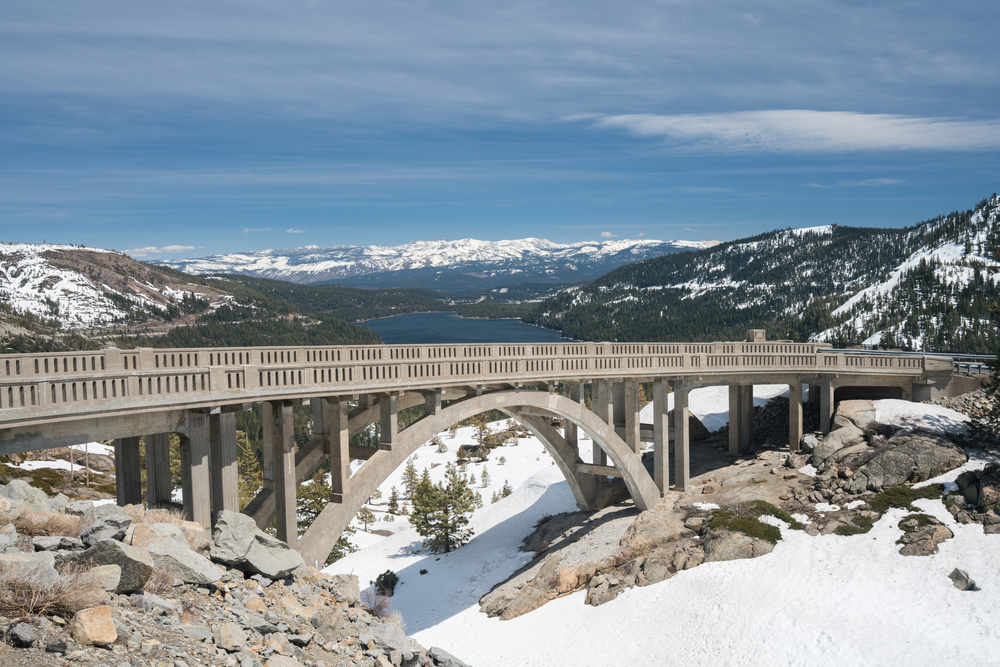 Donner Summit Bridge in Truckee, California, on a snowy day with mountains in background.