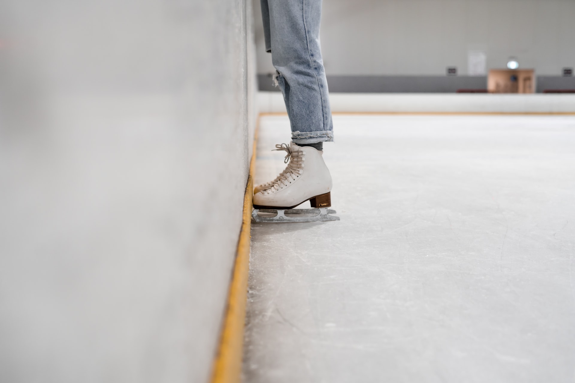 White ice skates up against the wall in an indoor rink.