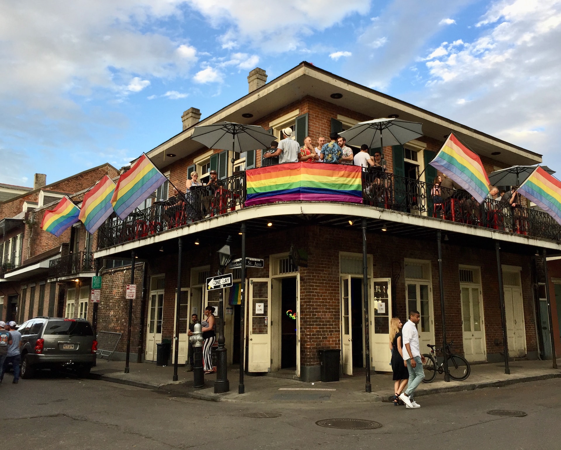 A second-floor restaurant with outdoor seating and rainbow flags in New Orleans.