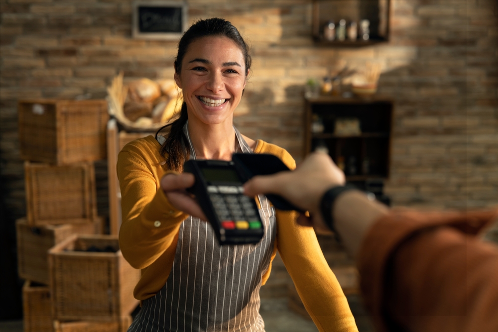 Woman holding credit card POS at a rustic-looking shop.
