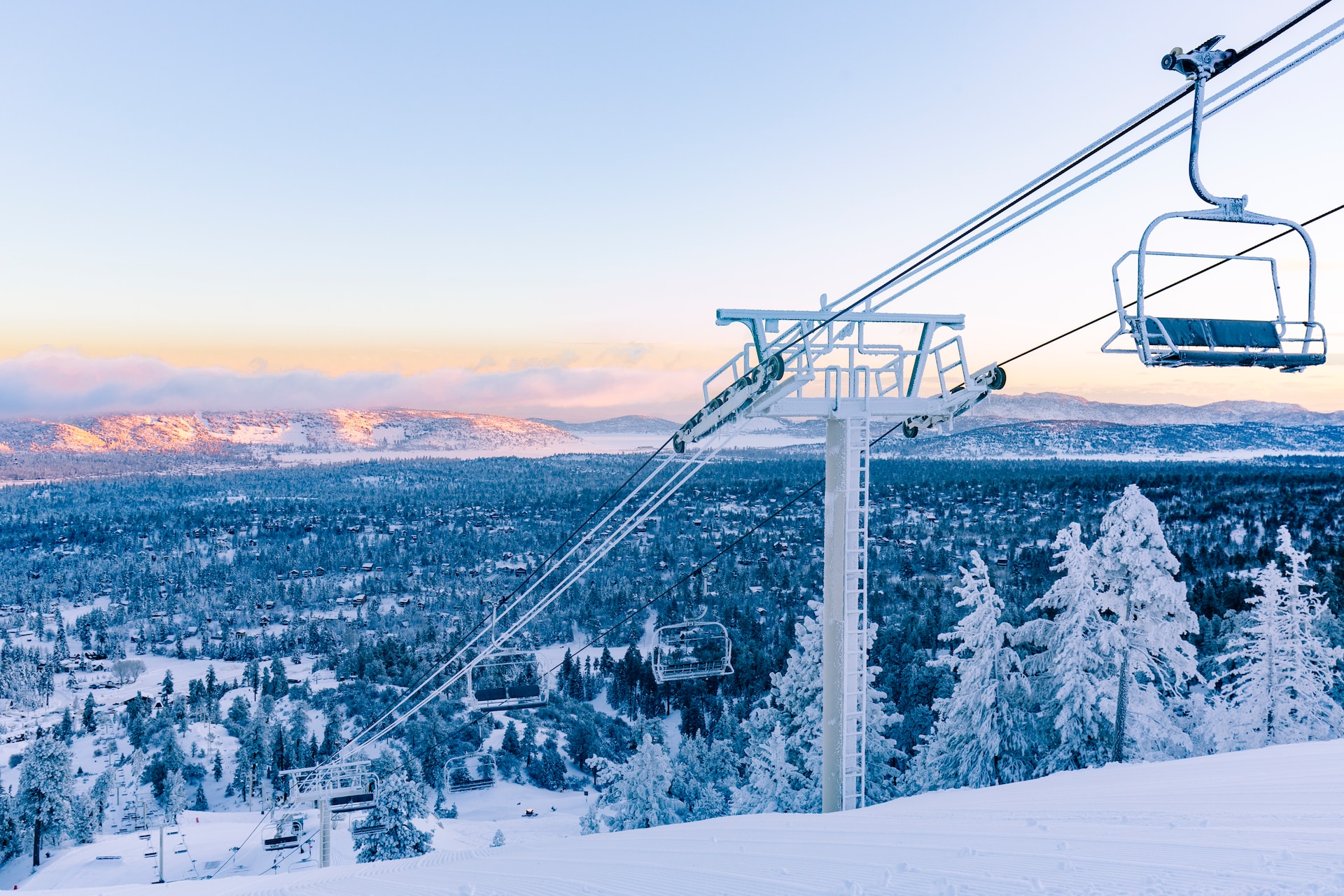 Ski lift over snowy mountain with snowy forest in background.