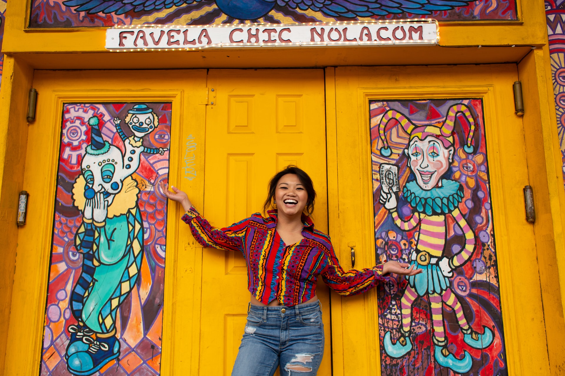 A smiling woman standing beside a bright yellow door.