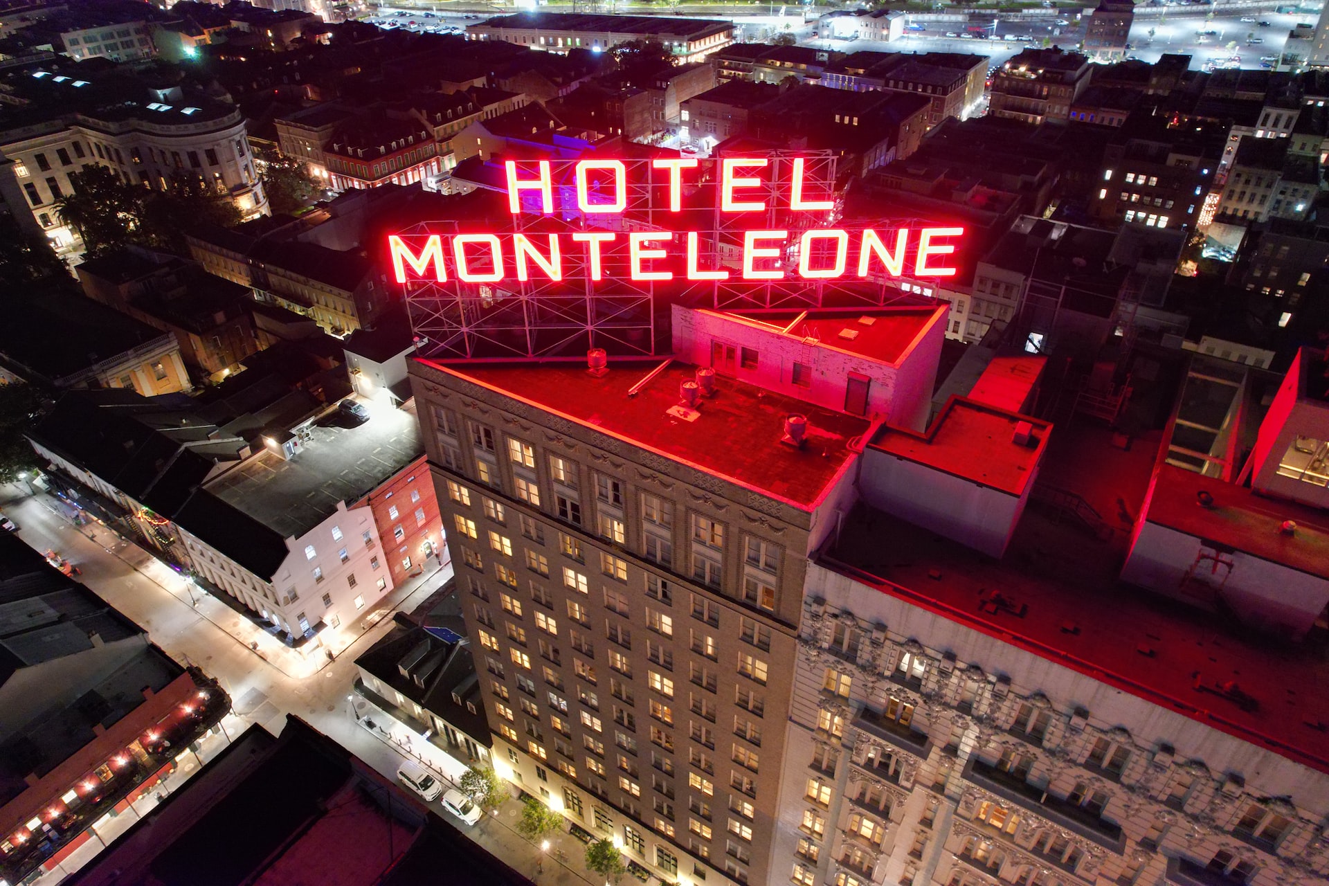 The Hotel Monteleone sign lit-up in big neon red lettering on the top of the building.