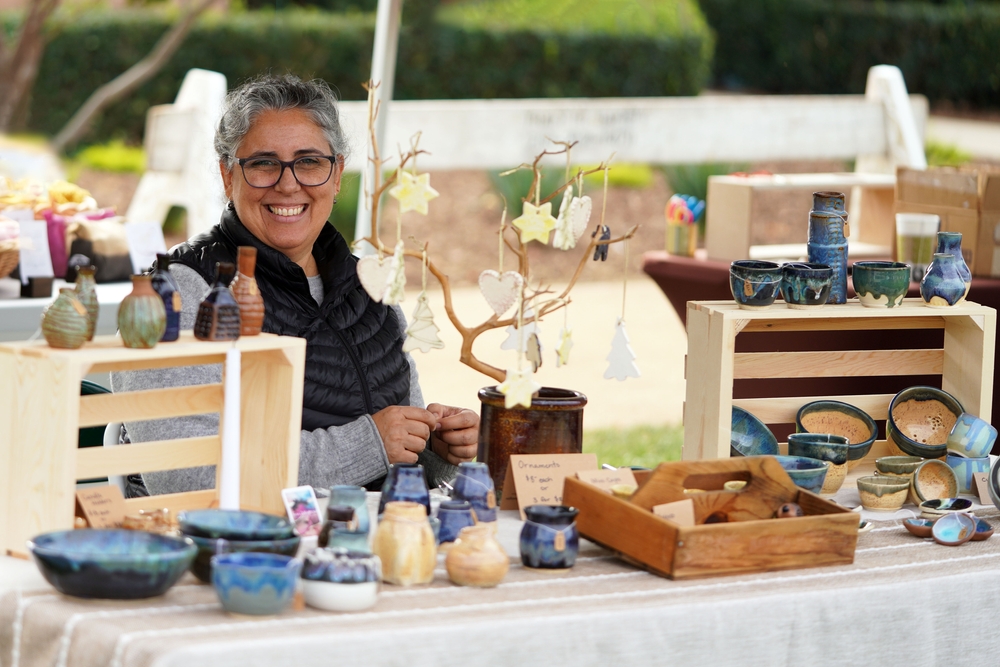 Woman with pottery display selling her ceramic bowls, vases, dishes, and ornaments at the crafts fair.