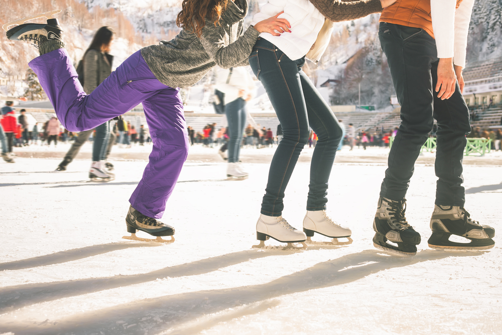 Teenagers (girls and boy) skating outdoors on an ice rink.