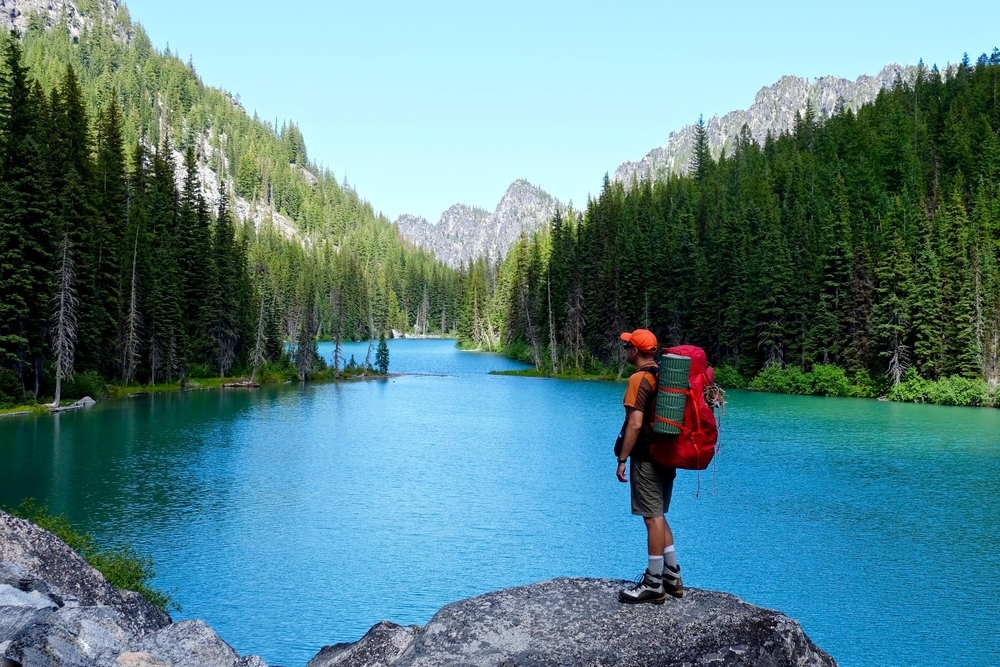 Male backpacker looking out at serene scene of Enchantment Lakes basin, Leavenworth, Washington.