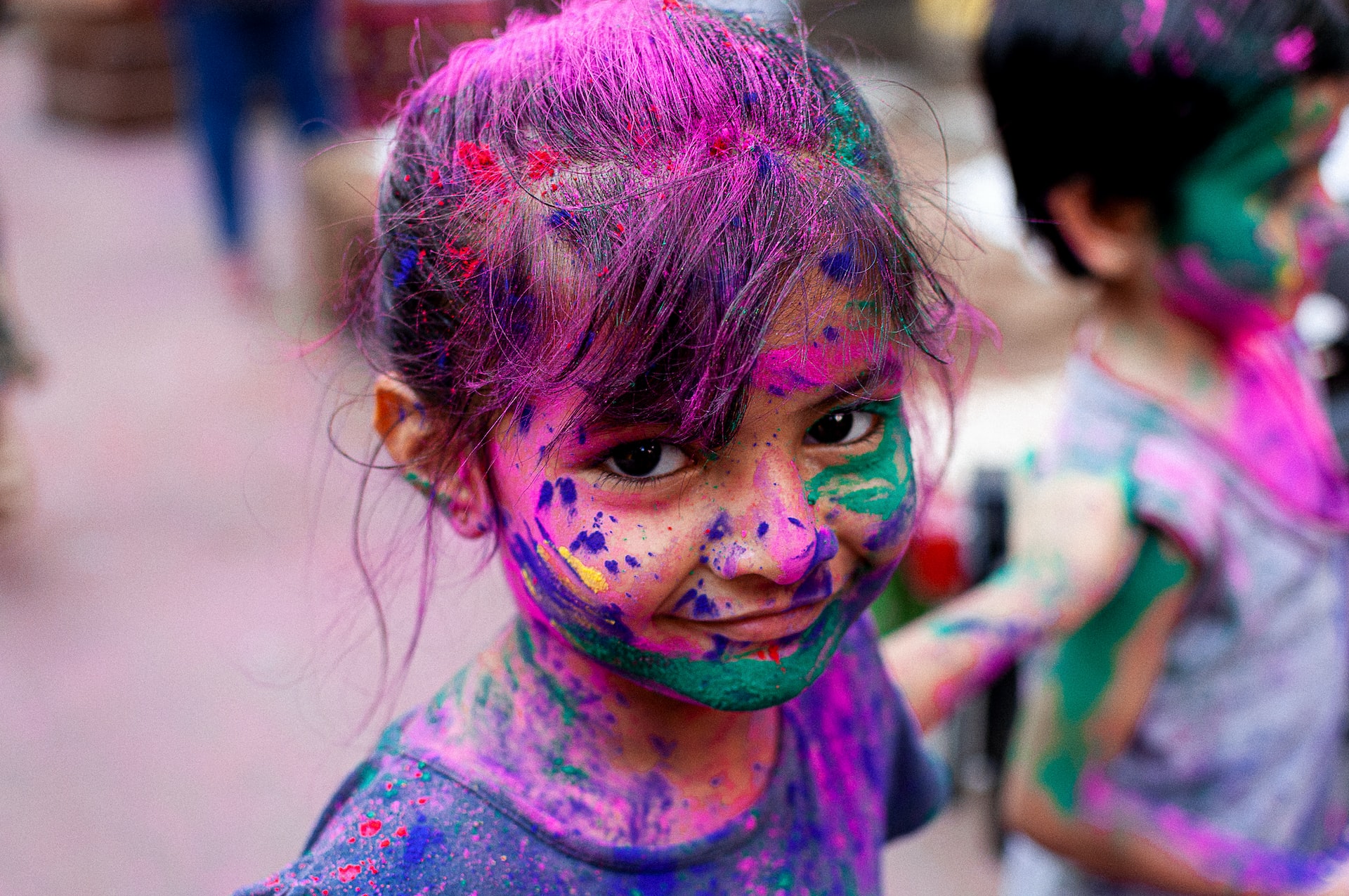 A young girl with a face full of colorful powder.