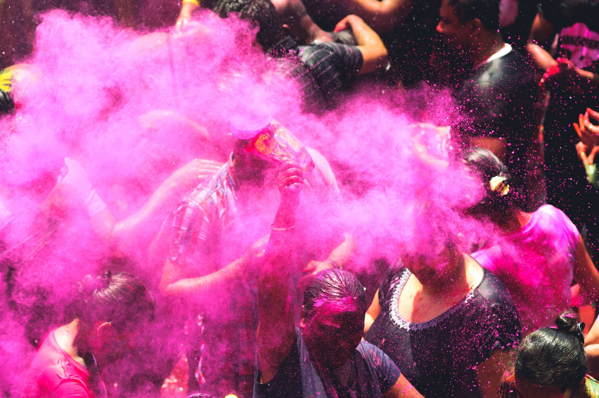 Pink powder bursting in the air above people's heads.