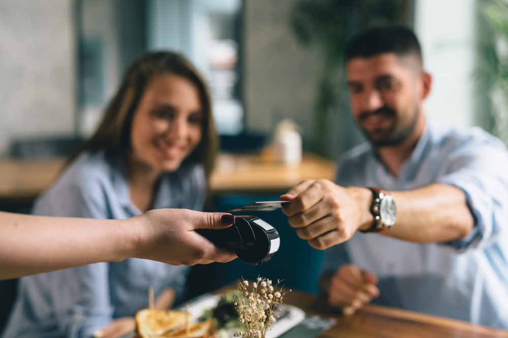 Man making payment with smartphone in restaurant.