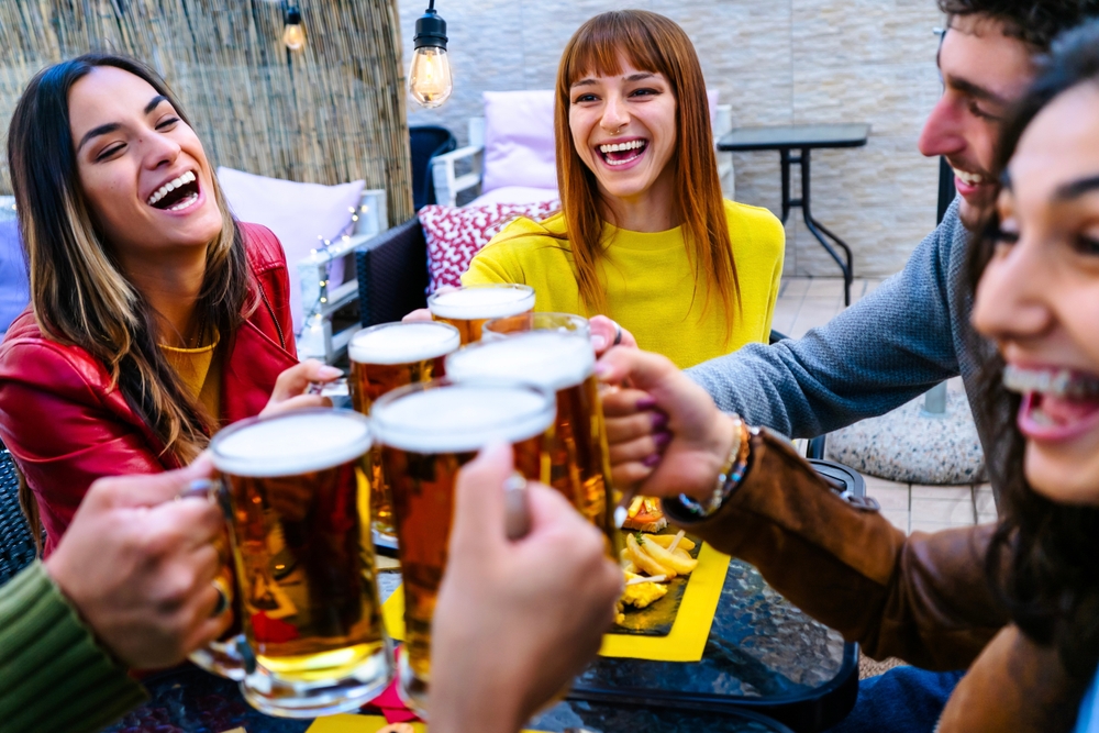 Happy smiling friends enjoying happy hour drinking beer.