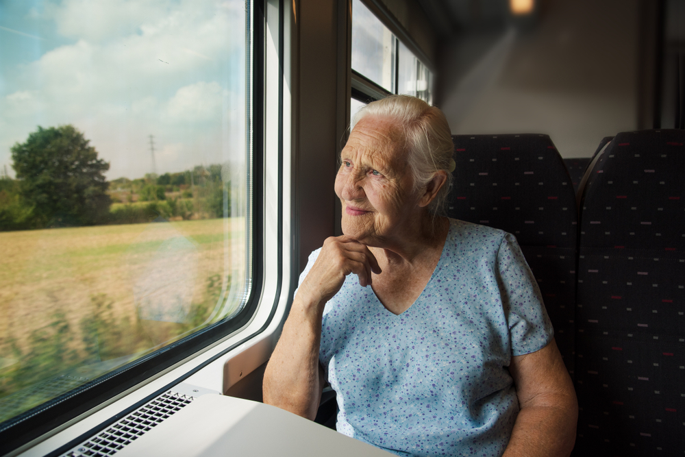 Portrait of a happy senior woman looking out the window on a train.