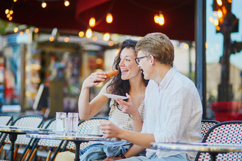 Happy romantic couple in Paris, drinking coffee in traditional Parisian outdoor cafe.