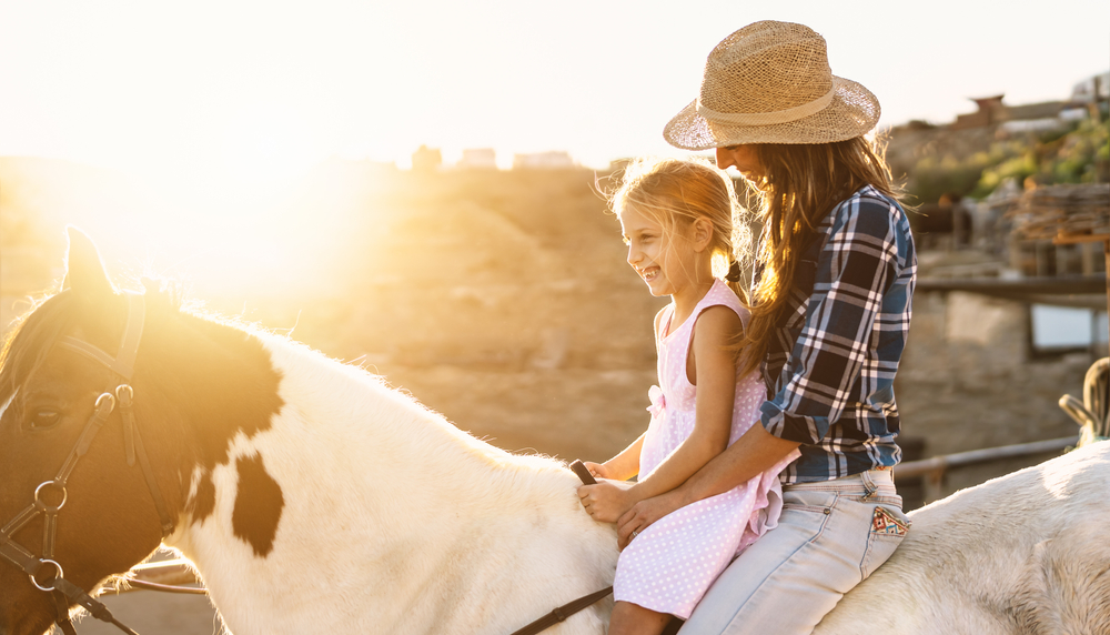 Mother and daughter riding a horse together.