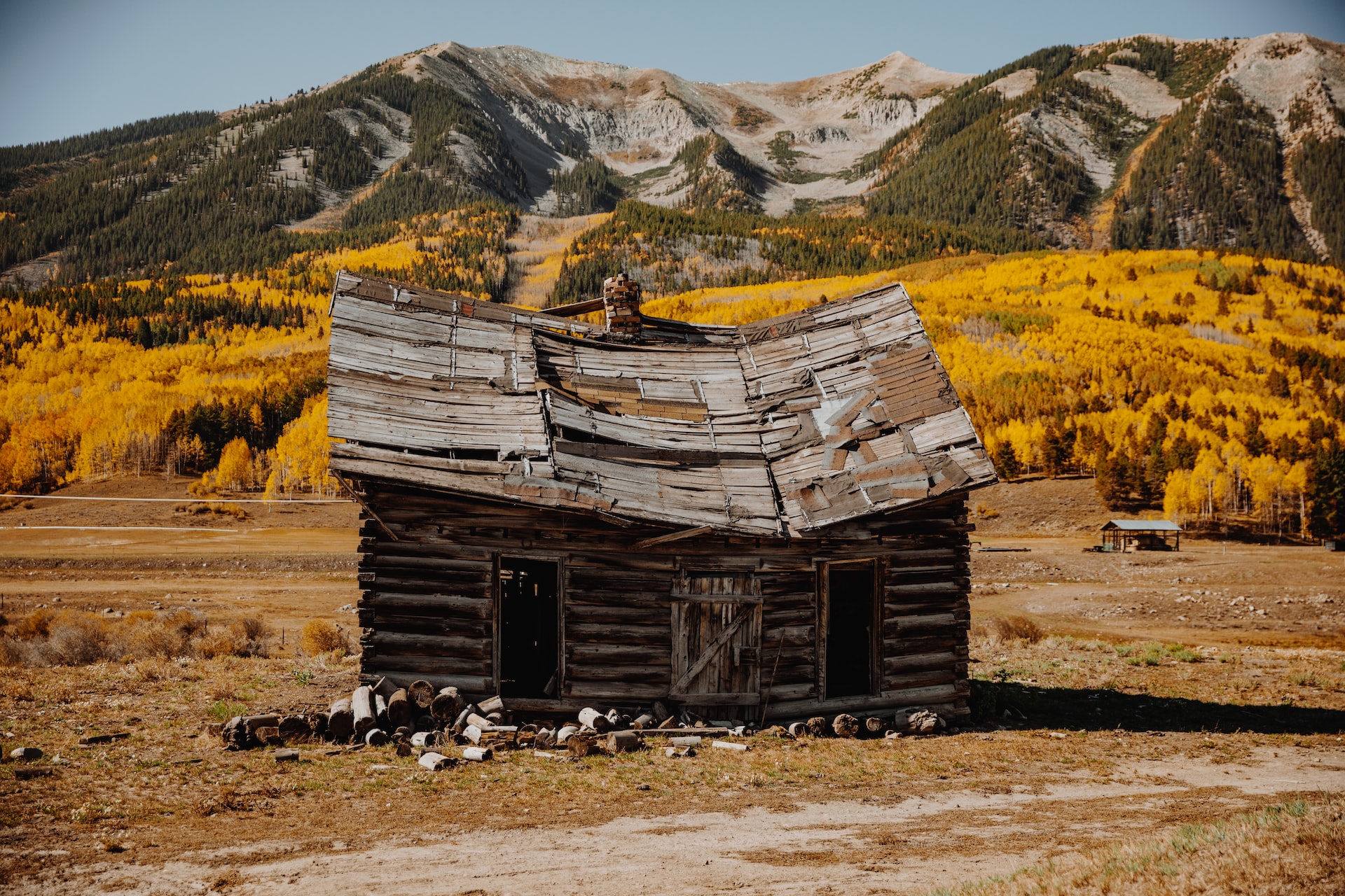A ramshackle old wooden cabin in Crested Butte with yellow leaves in the background.