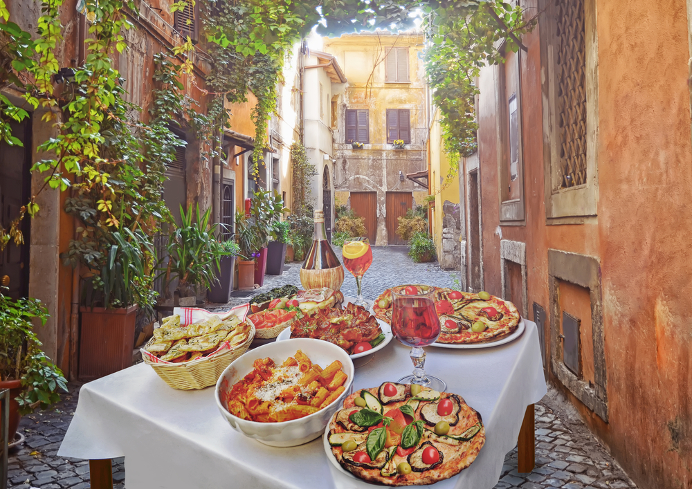 A beautiful spread on a white table clothed and wooden table on a bright street in Rome.
