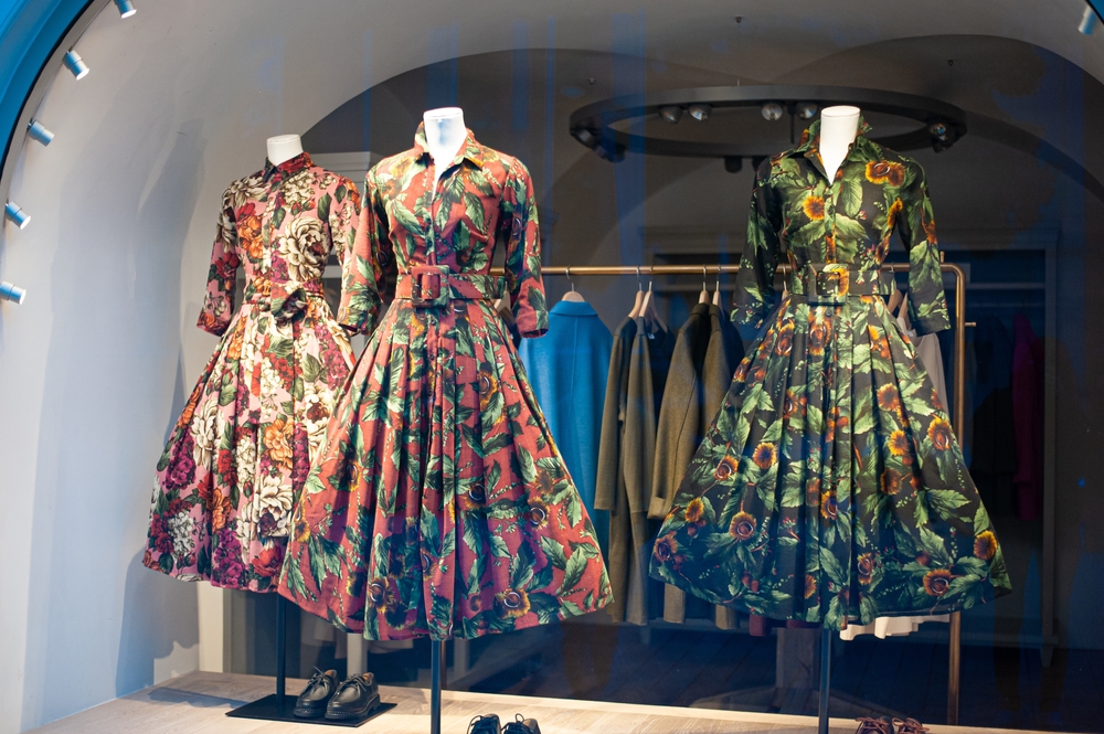 A storefront showcasing vintage floral print dresses and puffy skirts.