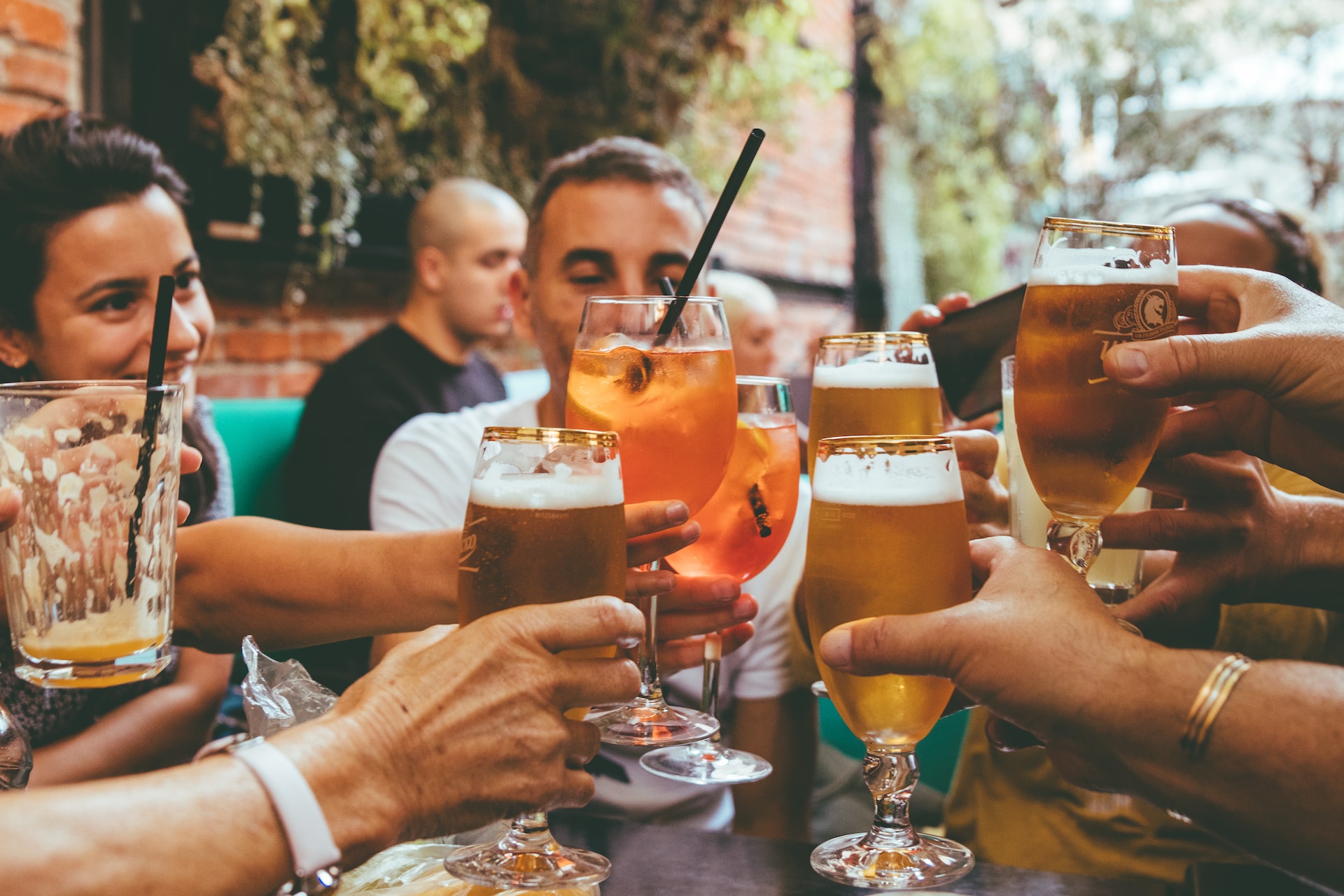 People sitting around a table tapping glasses together for a round of cheers.