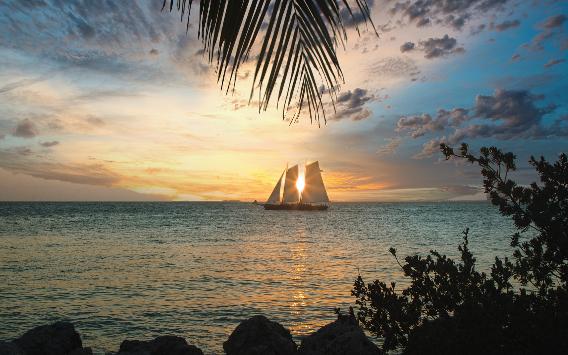 A sailboat with the sun shining through its sail.