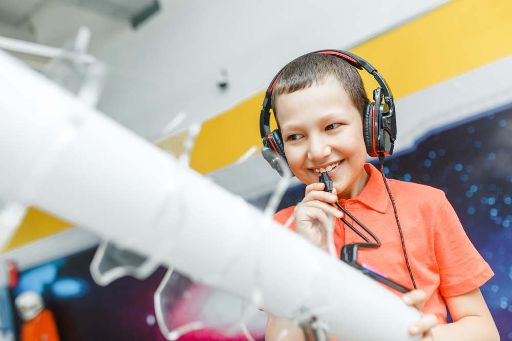 Boy using headphones and mic at an interactive museum.