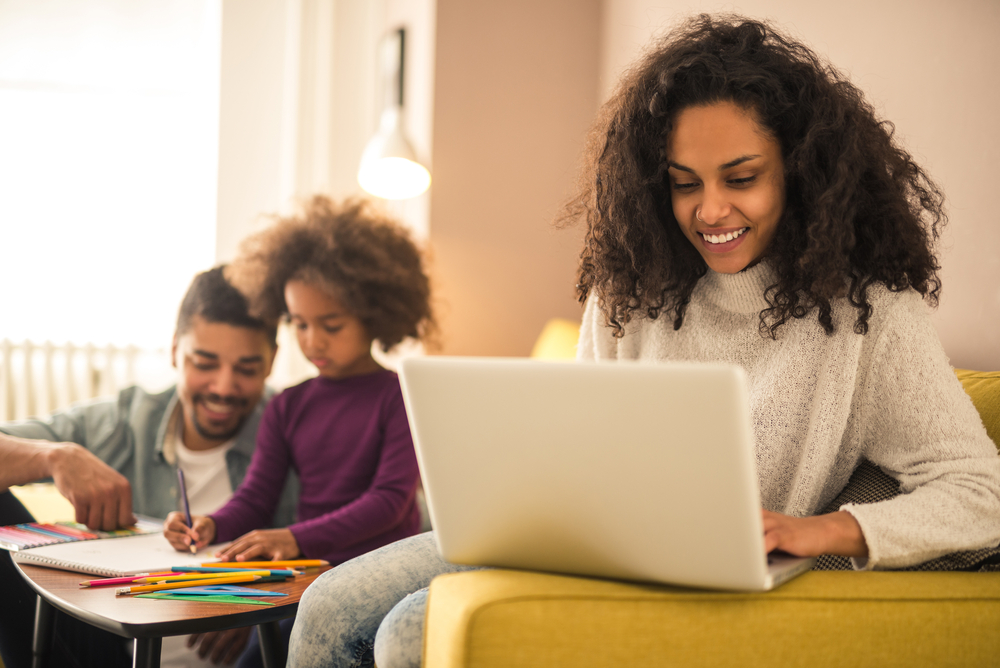 Mother working from home while dad and daughter having fun.