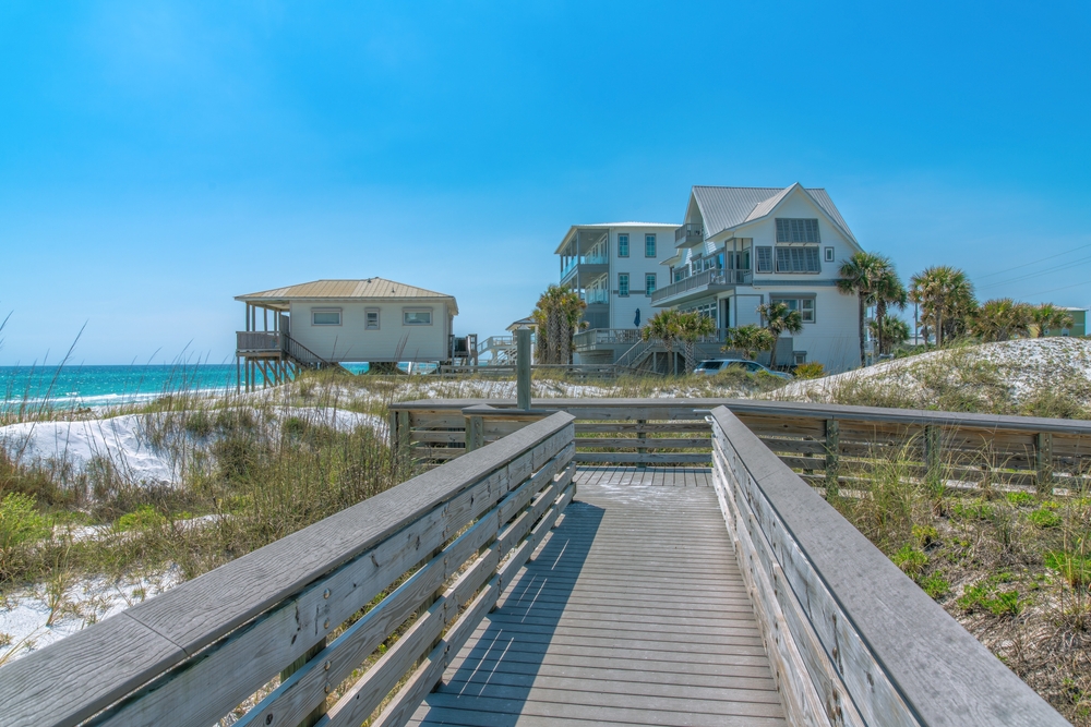 View of beach houses from a wooden boardwalk on a beach.