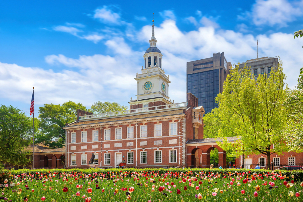 Independence Hall with a lawn full of red and yellow flowers on a spring day.