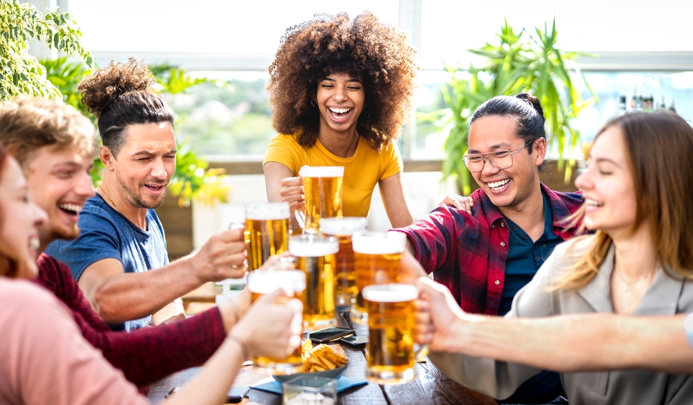 Young trendy people drinking and toasting beer at brewery.