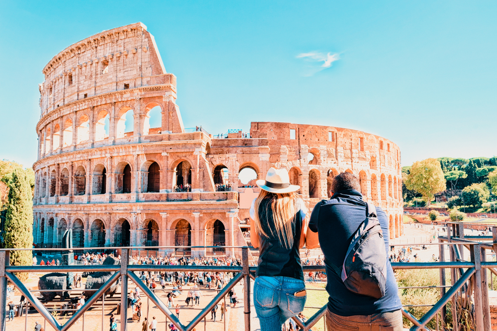 Young couple enjoying the view at Colosseum in the old city center of Rome, Italy. 