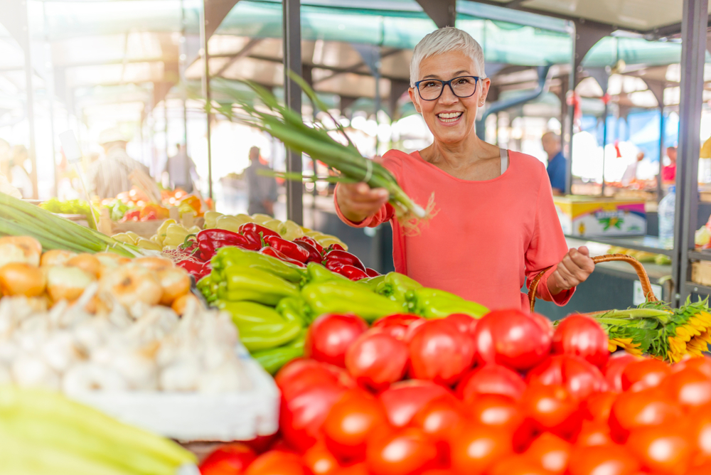 Senior woman buying vegetables at a farmers' market.