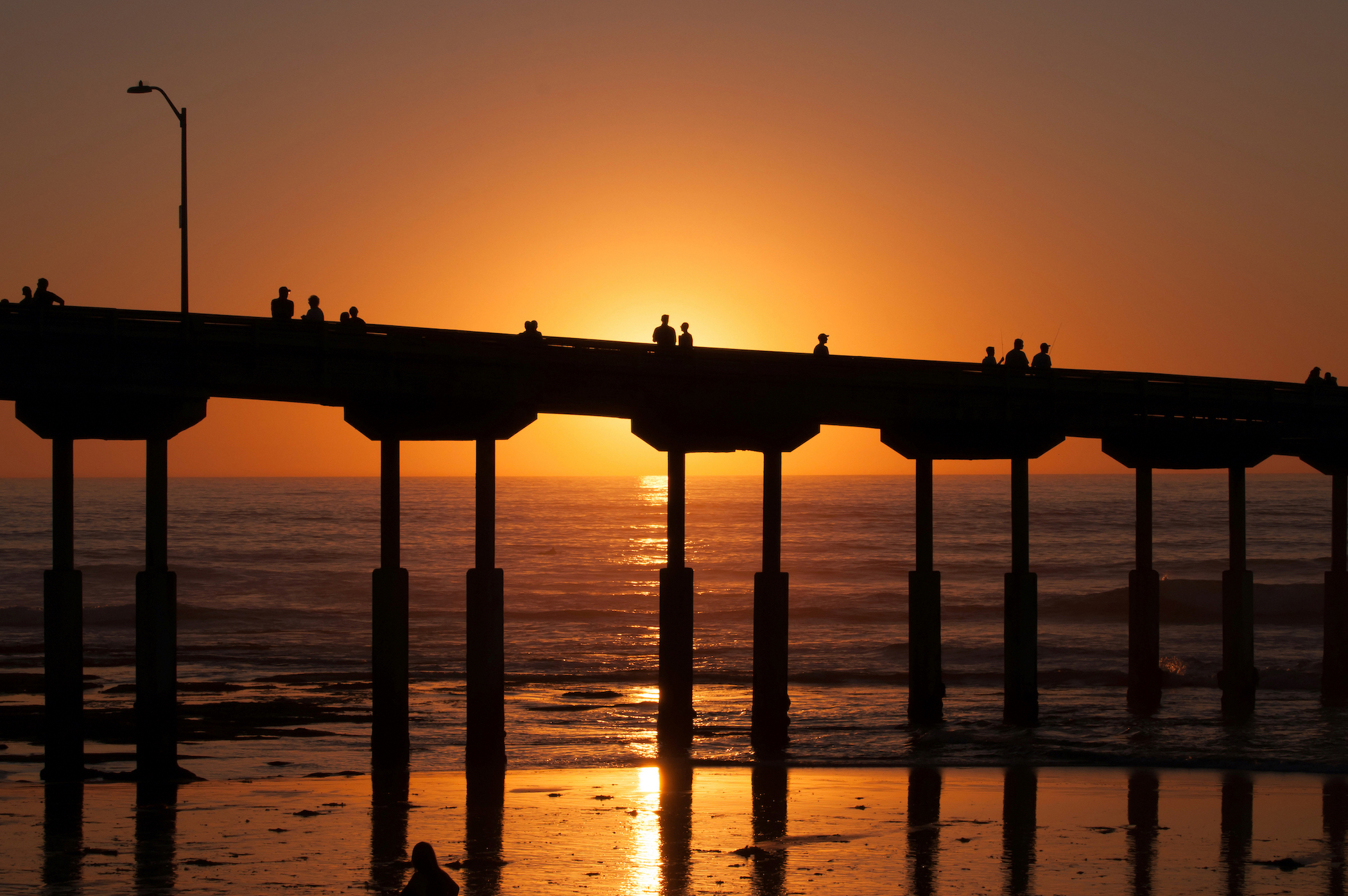 The silhouettes of people on a pier at dusk.