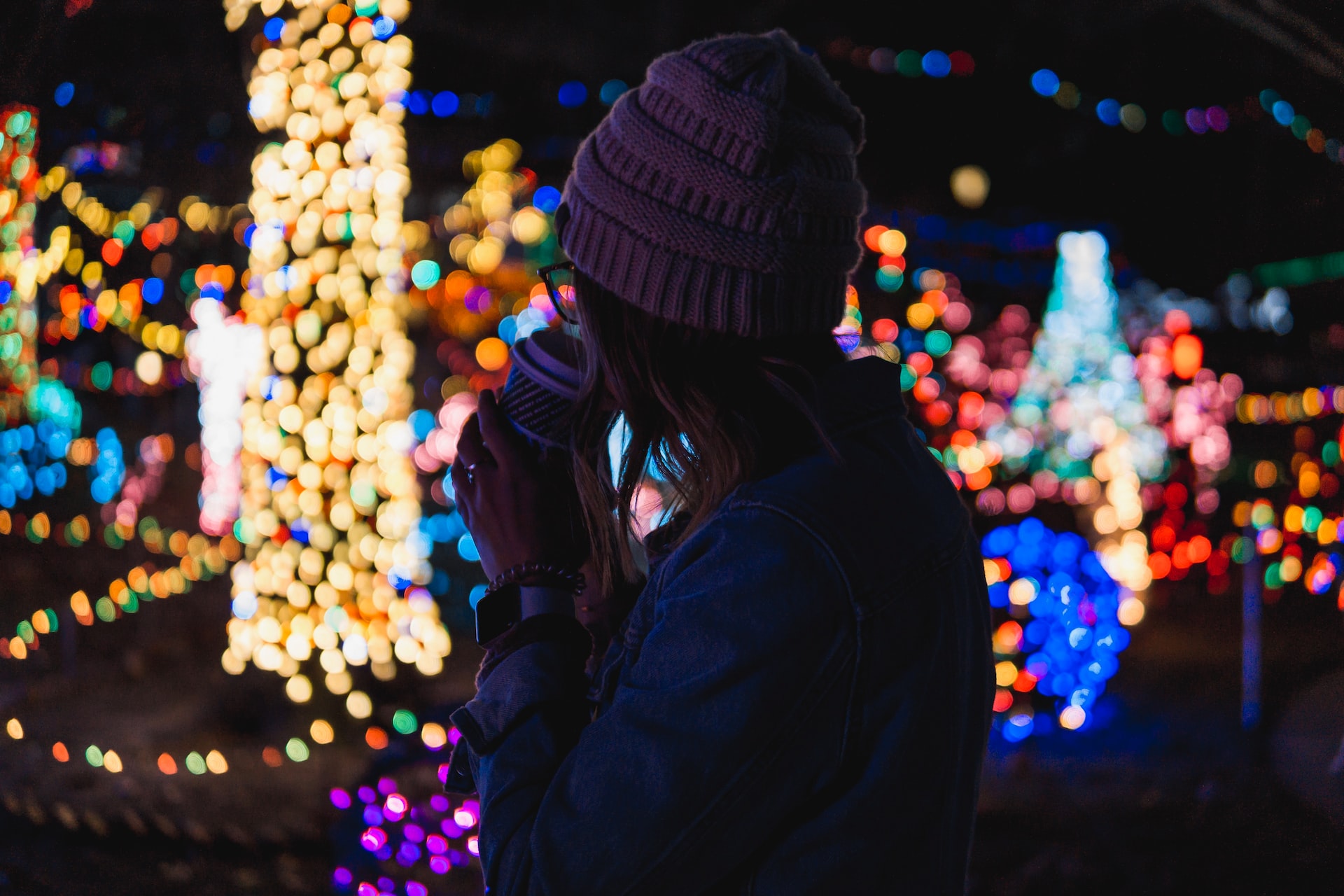 Bokeh photography of a woman looking at Christmas lights behind her.