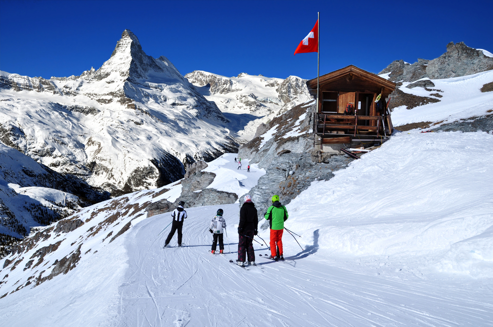 Skiers on the way to the ski slopes in the Swiss Alps on a sunny day with the Matterhorn in the distance.