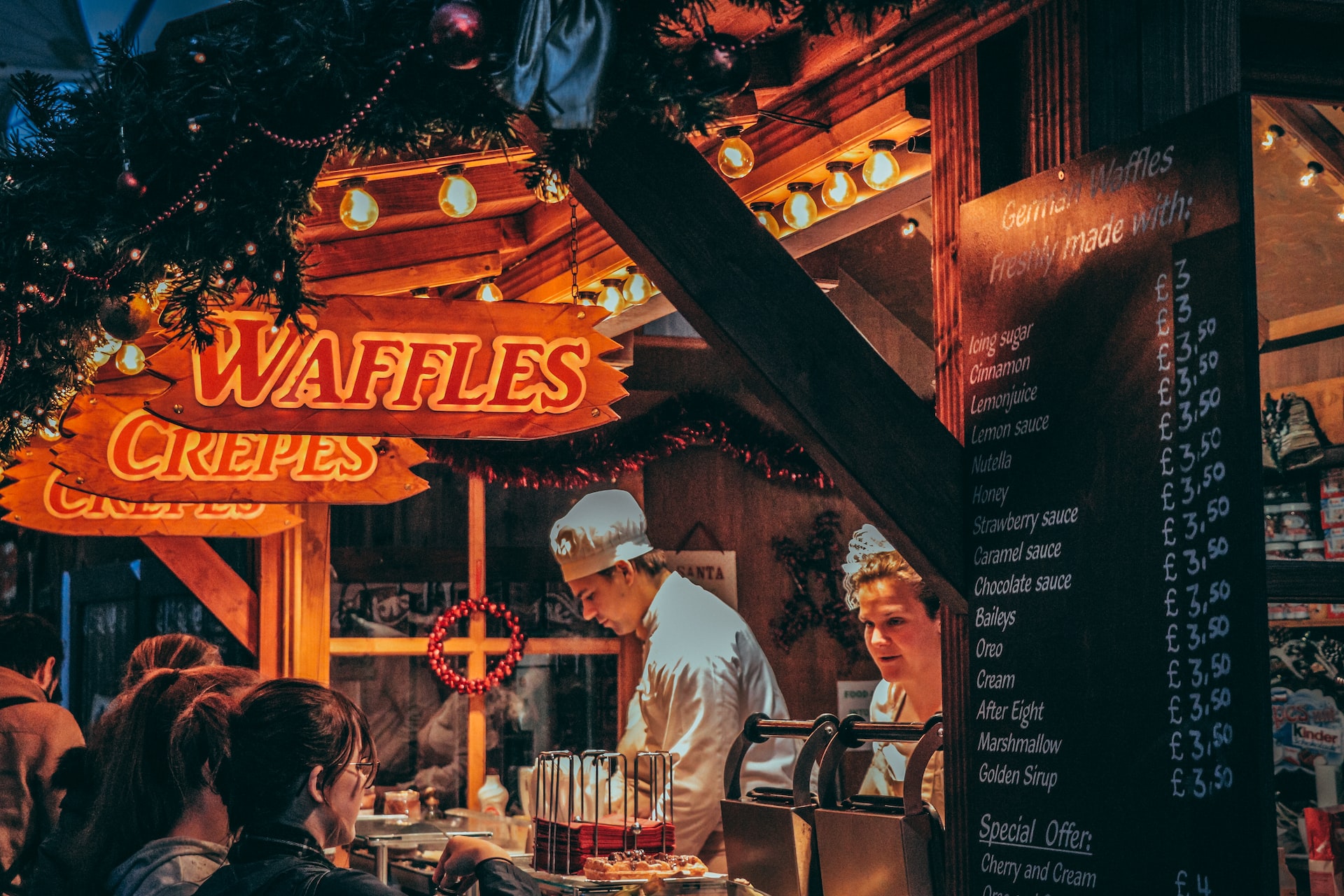 People browsing food at a vendor at a Christmas market.