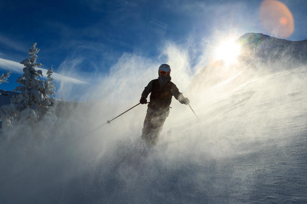 A skier surrounded by swirling powder in winter on the mountain.