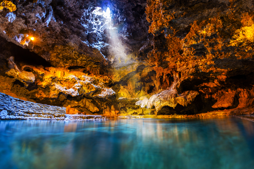 Beam of light shines through an opening in the underground cave onto the thermal hotspring waters at Cave and Basin National Historic Site, the birthplace of Canada's national parks in Banff.